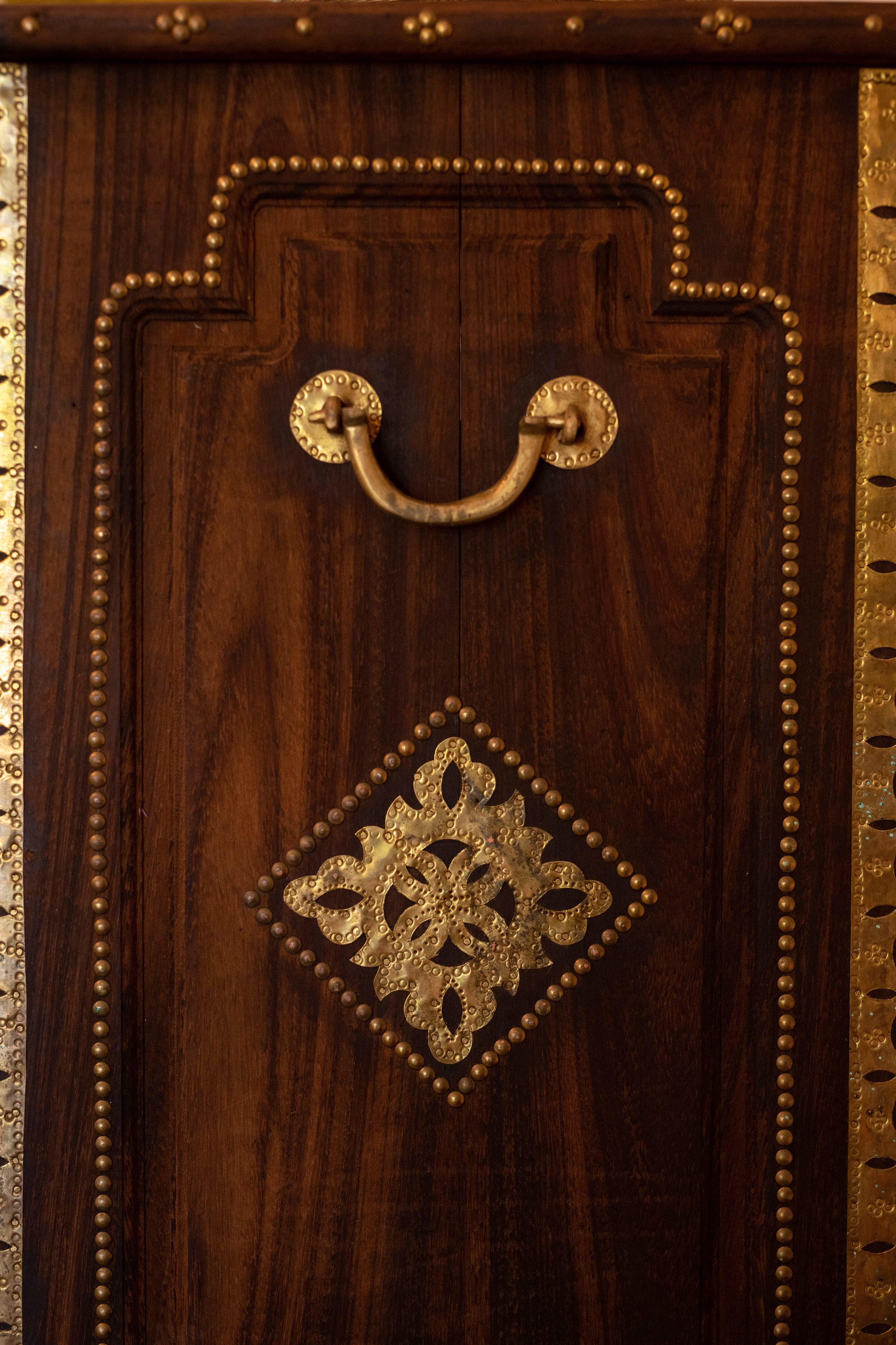 Une porte en bois avec une poignée en laiton et des éléments décoratifs en métal.