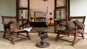 A room with two wooden chairs with patterned cushions, a small round table, and a decorative sculpture. - Tikitam Palms Boutique Hotel (Kiwengwa)