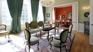 A dining area with a round table, six chairs, and a chandelier.