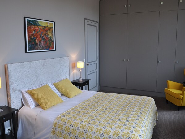 A hotel room with a bed, a nightstand, a lamp, a wardrobe, and a chair.