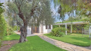 A modern house with a well-maintained garden, a stone pathway, and a pergola.