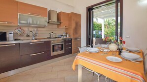 A modern kitchen with stainless steel appliances, wooden cabinets, and a dining area with a table set for two.