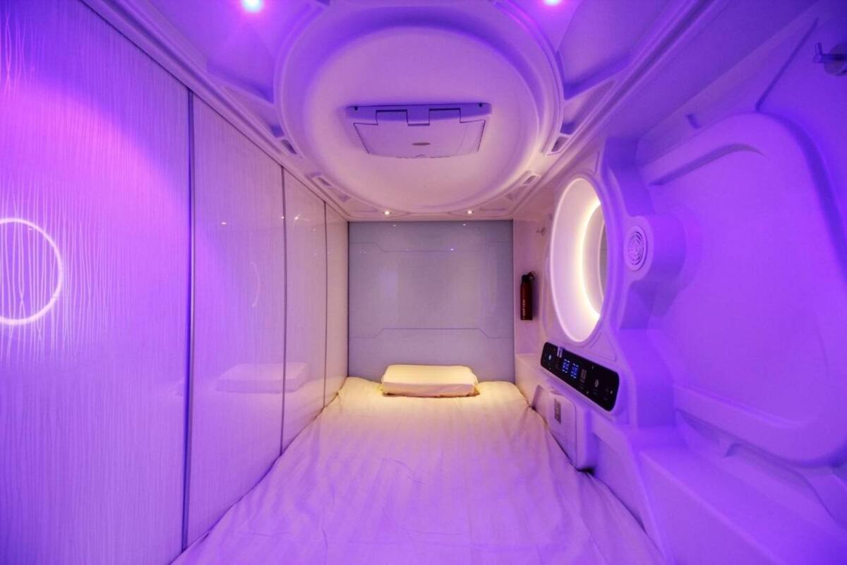 Une pièce comprenant un lit, un panneau de commande et un luminaire circulaire fixé au mur.
