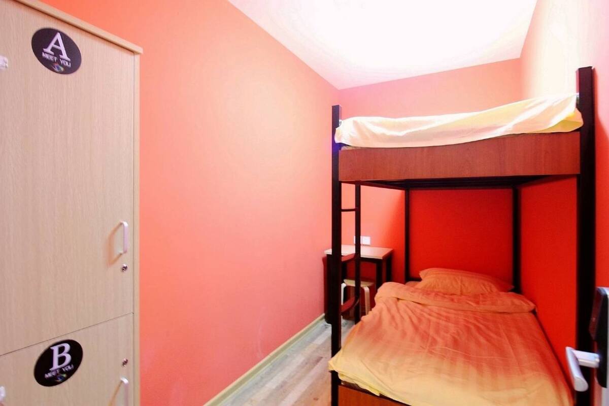 Une chambre avec un lit superposé en bois, un bureau et une armoire à deux compartiments, étiquetés A et B.