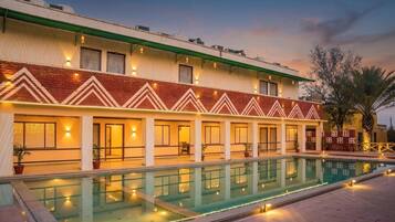 Un hotel con piscina, varias habitaciones con ventanas y techo verde.
