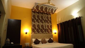 A hotel room with a bed, a nightstand, a ceiling fan, and patterned curtains.