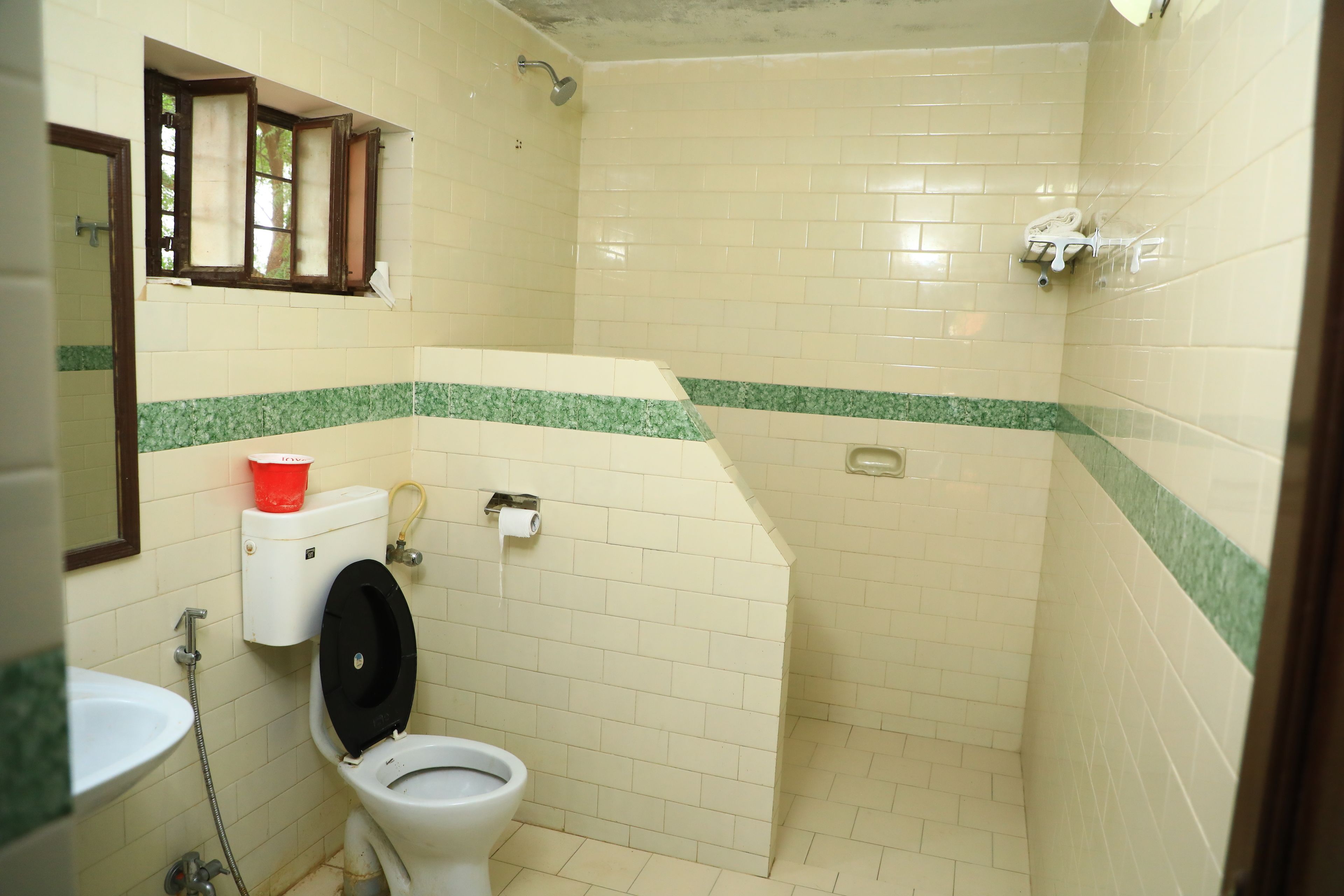 A small, tiled bathroom with a toilet, sink, and shower.