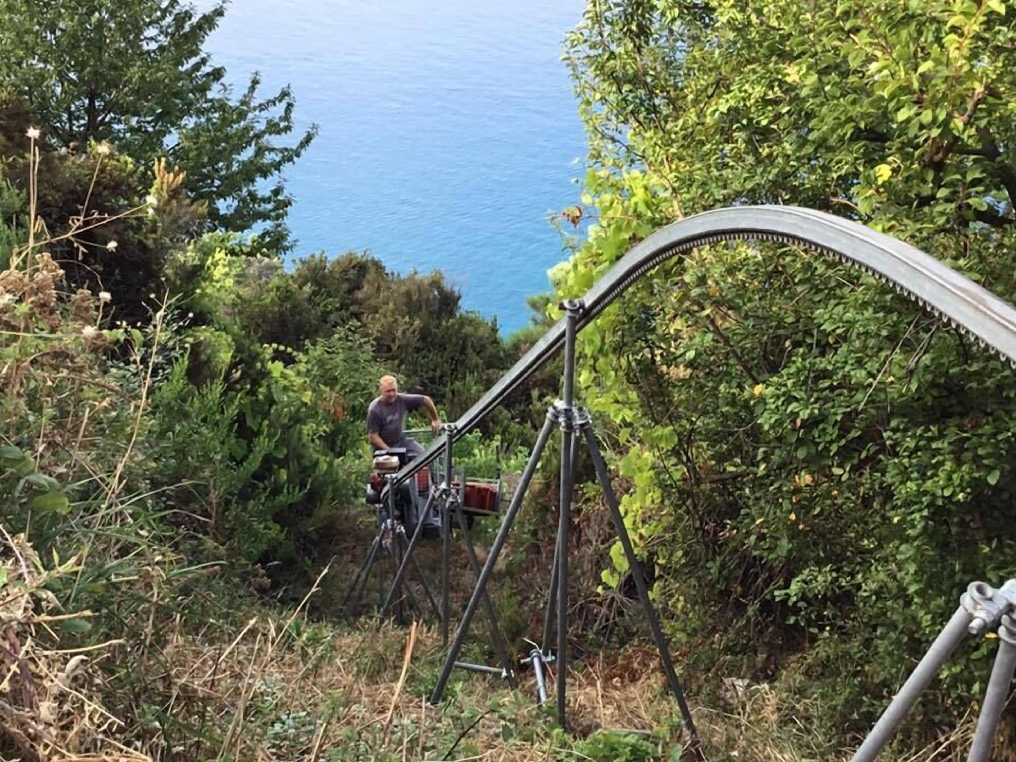 A person on a metal structure with a camera on a tripod, overlooking a body of water.