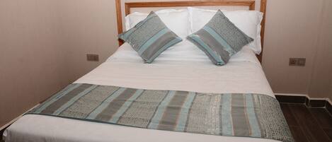 A neatly made bed with a patterned bedspread and two pillows.