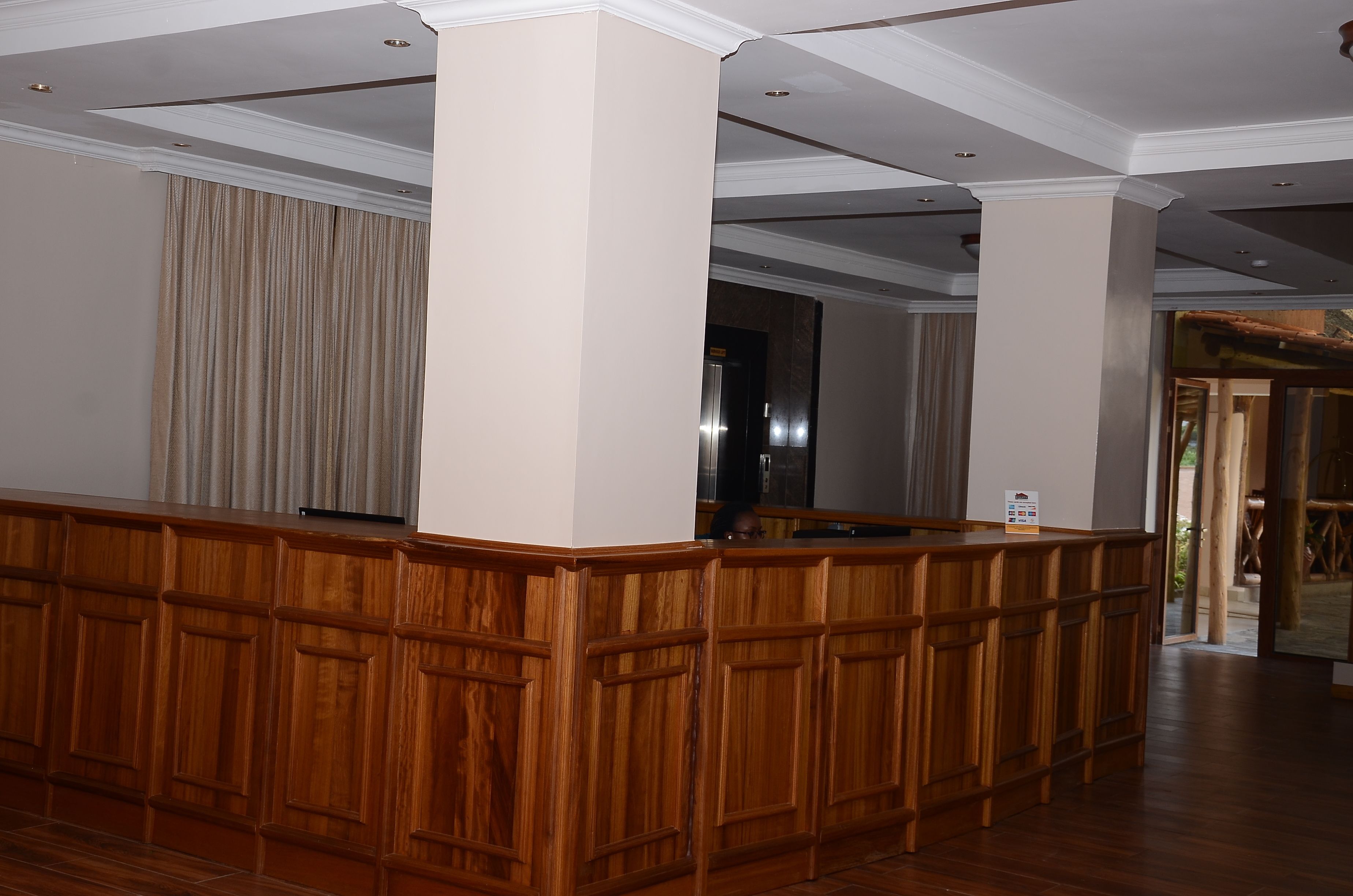 Zona de recepción con paneles de madera, una barra de atención y vista a un pasillo con una puerta.