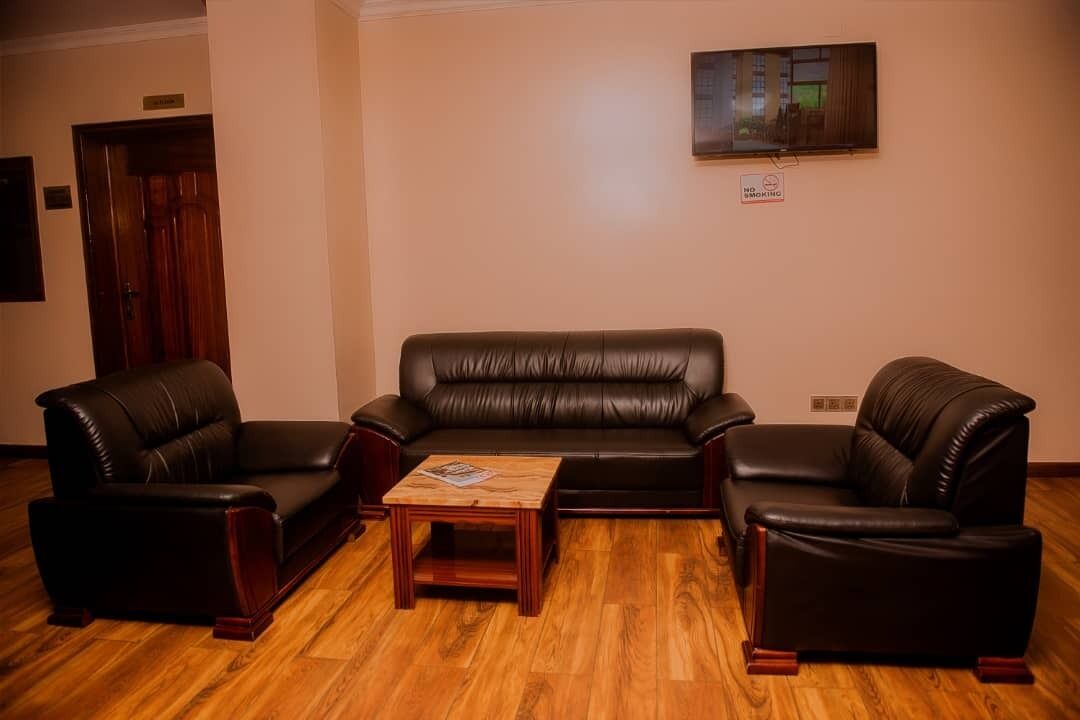 A living room with a black leather sofa, two armchairs, and a wooden coffee table.