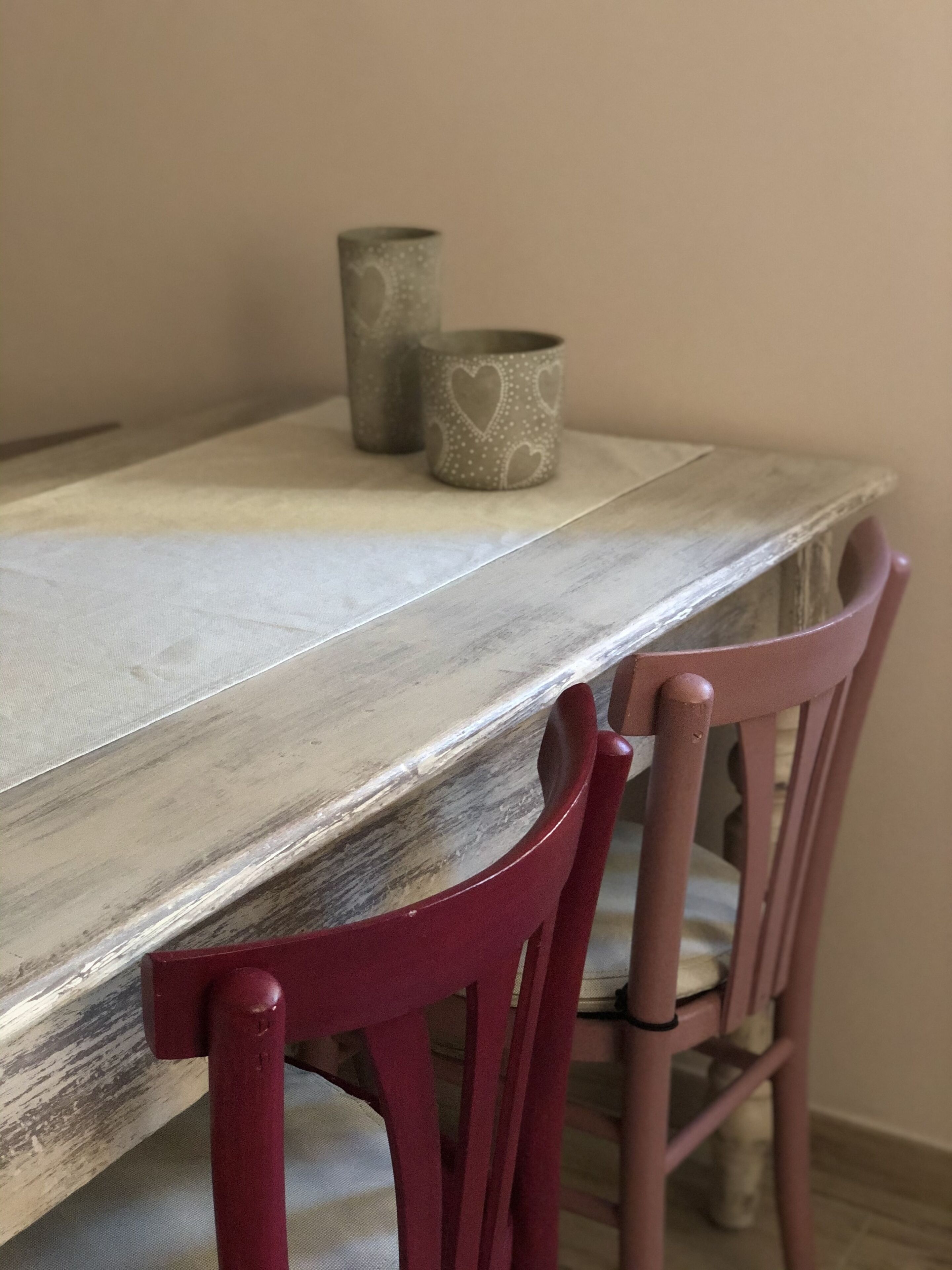 Una mesa de madera con dos tazas con forma de corazón y una silla roja.