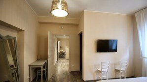 Una habitación de hotel con una cama, un escritorio, dos sillas, un televisor y un espejo.