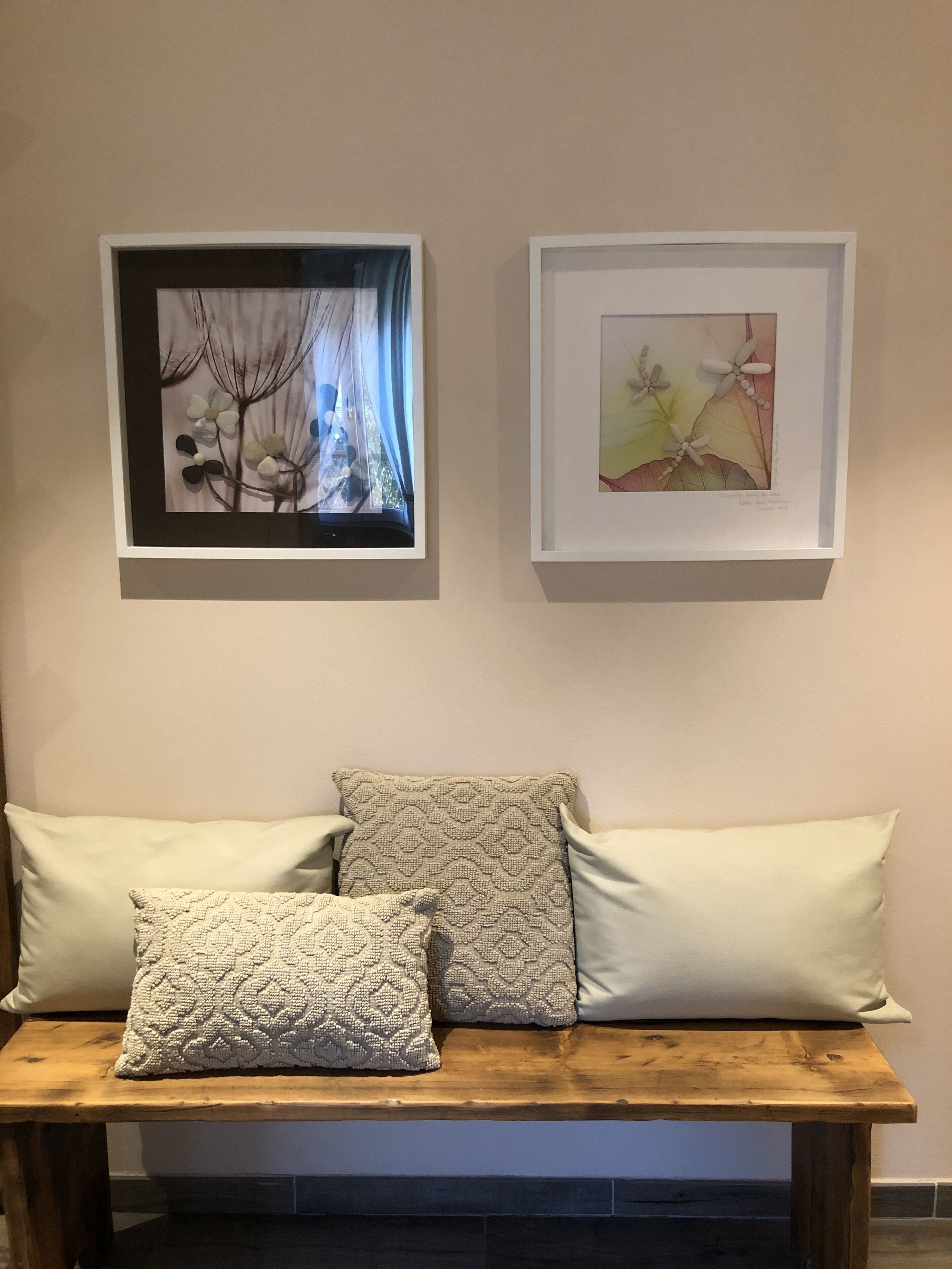 A room with a wooden bench and two framed artworks above it.