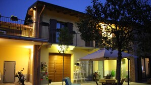 Un edificio residencial con balcón, mobiliario exterior y una motocicleta estacionada afuera.