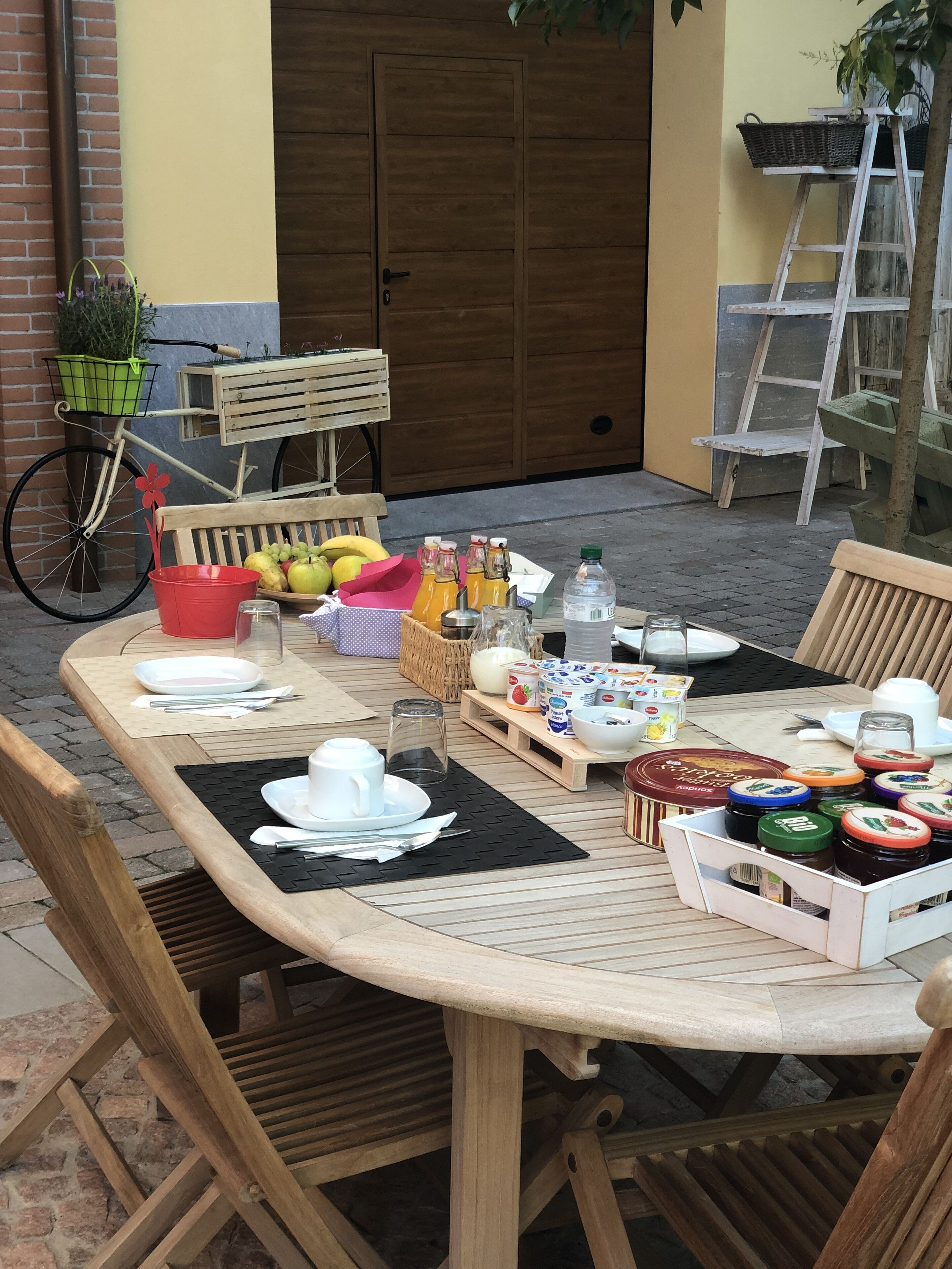 Una mesa de madera dispuesta para una comida, con platos, cubiertos y diferentes alimentos.