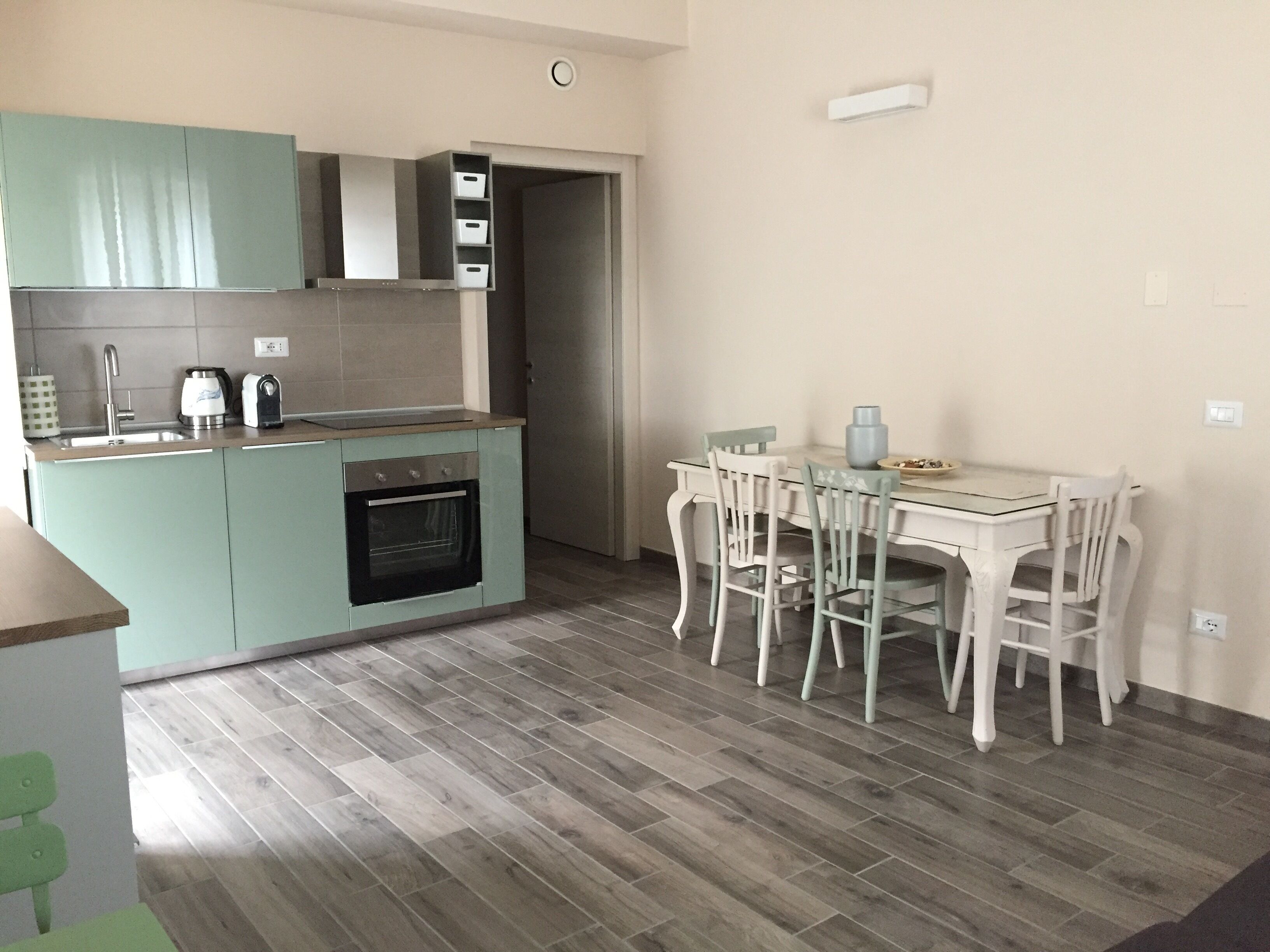 A compact kitchen with a dining area, featuring a built-in oven, a sink, and a small dining table with chairs.