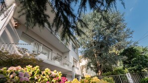 A multi-story building with balconies, surrounded by trees and flowering plants. - VILLA DUE GIARDINI (Padova)
