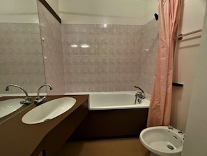 A bathroom with two sinks, a bathtub, and a shower curtain.