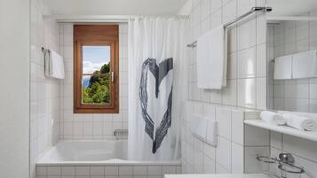 A modern bathroom with a bathtub, a window with a view of greenery, and a white sink with a mirror.