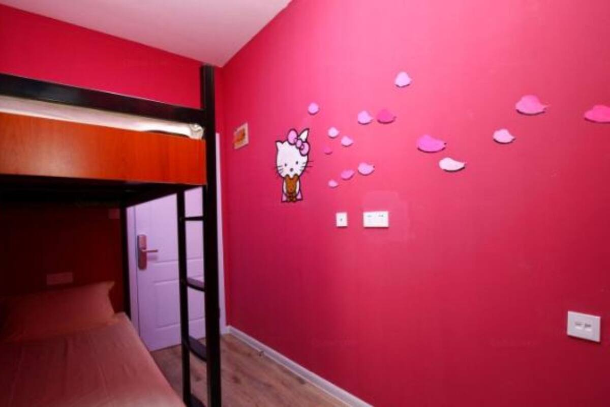 Une chambre avec un lit superposé, un mur rose et une décoration à l’effigie de Hello Kitty.