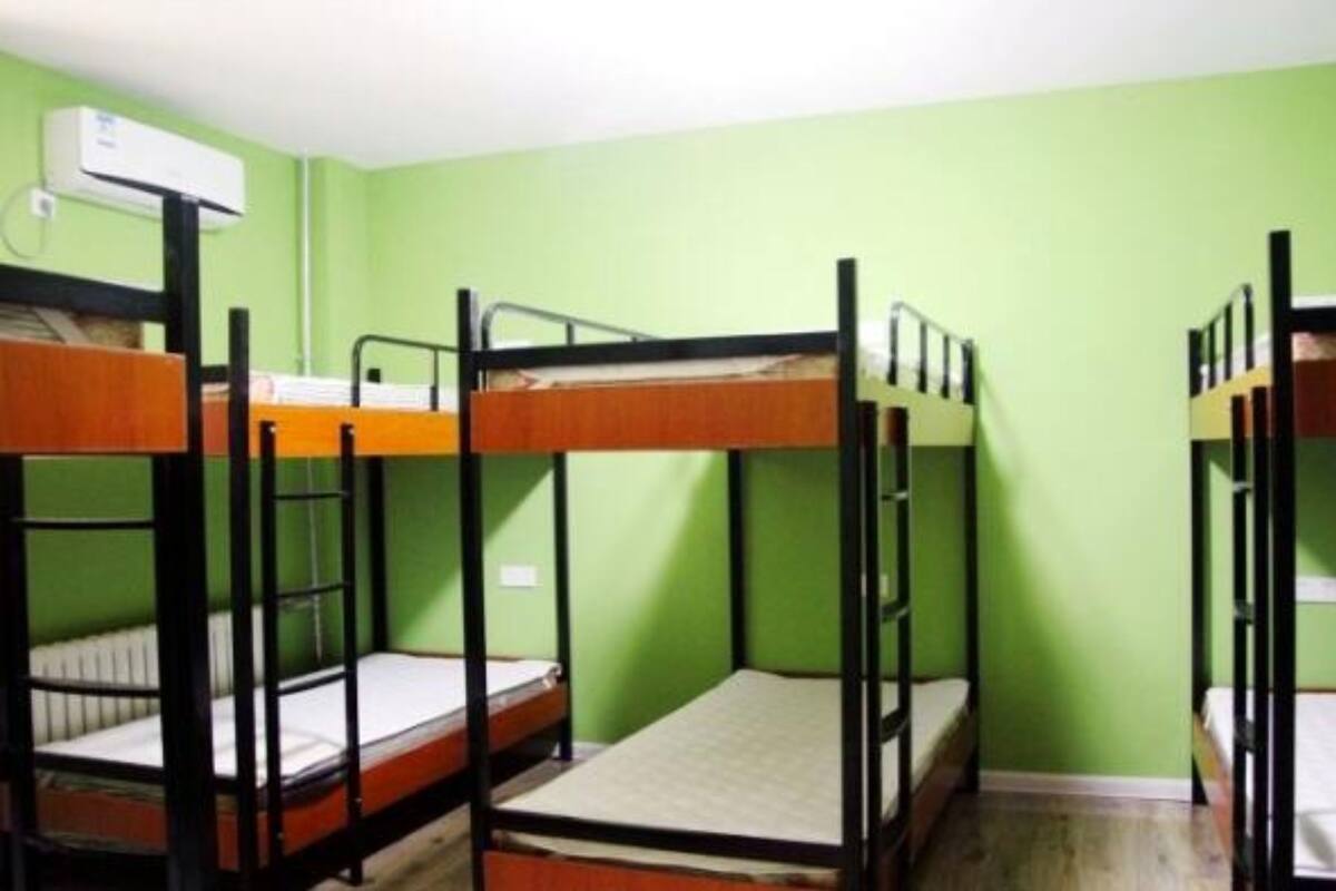 Une chambre de dortoir avec des lits superposés, un mur vert et un appareil de climatisation.