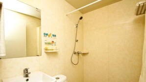 A bathroom with a sink, toilet, and shower. There is a towel hanging on the wall and a shelf with toiletries. - Meet int'l Youth Hostel Zhejiang Rd (Qingdao)