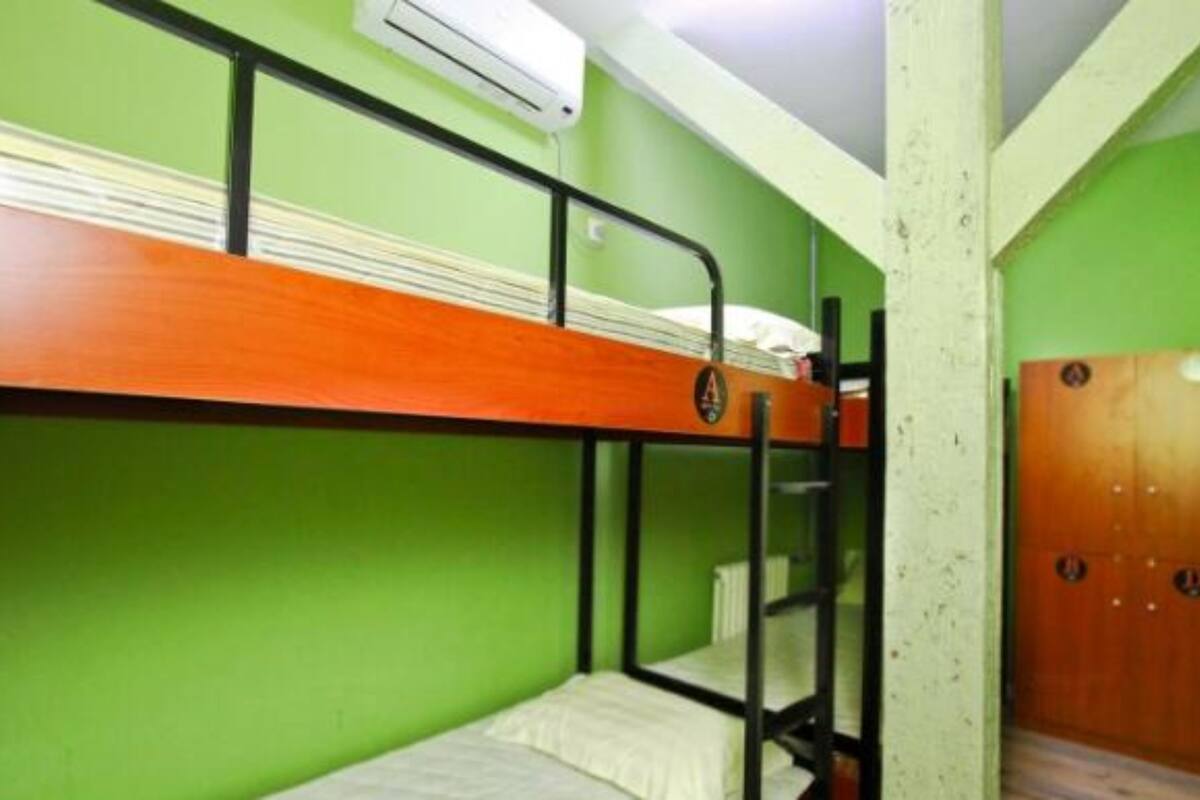 Une chambre avec des lits superposés, des murs verts, une porte en bois et un appareil de climatisation.