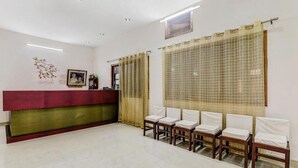 Un área de recepción con mostrador, varias sillas y piso de baldosas.