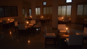 Una habitación con poca luz, con varias mesas y sillas, algunas con velas.