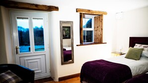 Een slaapkamer met een bed, een stoel, een raam en een spiegel.