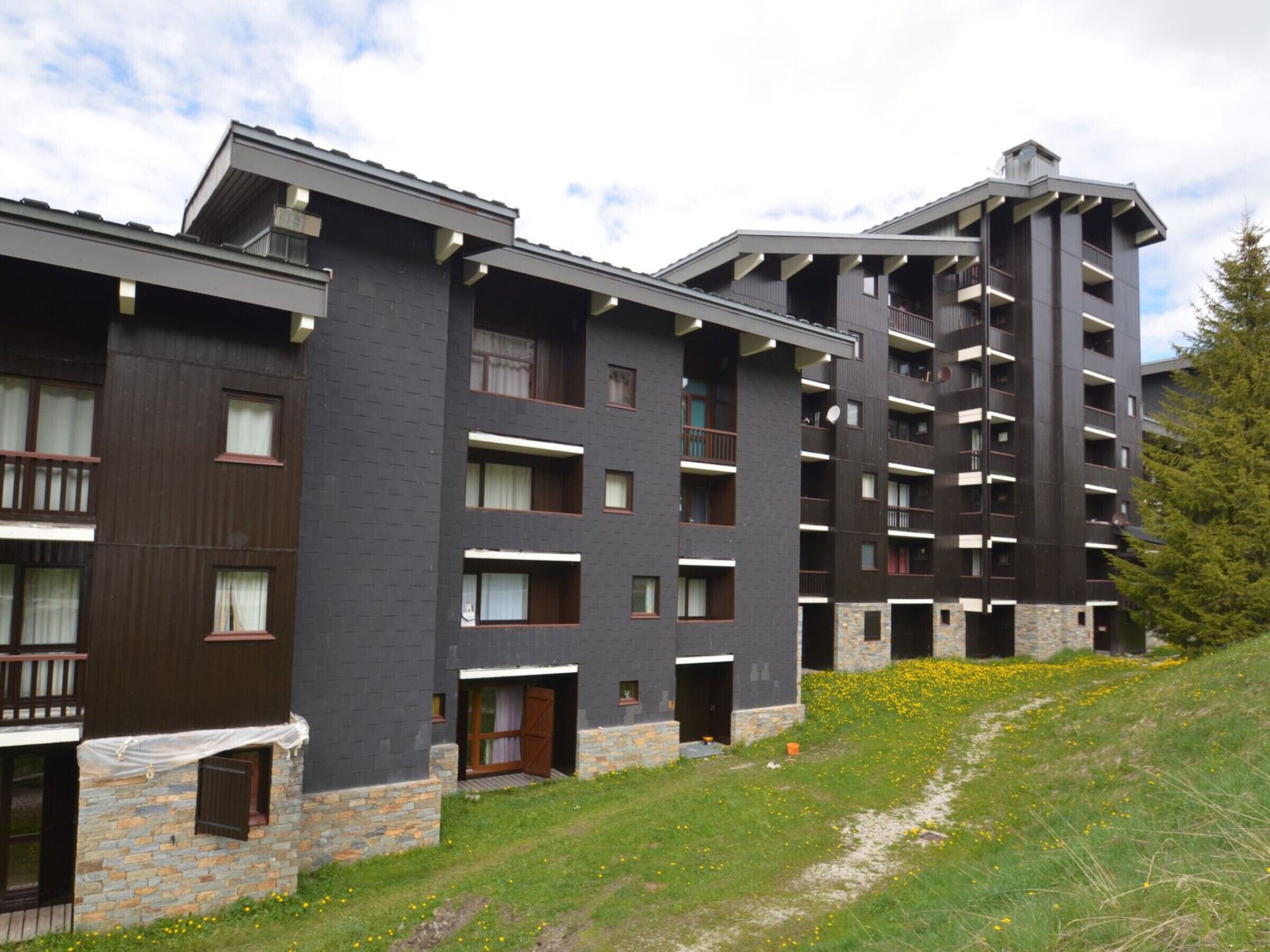 Un hotel de varios pisos con diseño moderno, que cuenta con balcones y fachada de piedra.