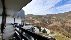 A balcony with a view of a mountainous landscape, a road, and a building with a modern design.