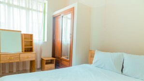 Een slaapkamer met een bed, een houten dressoir en een kledingkast.
