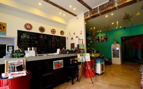A bar area with a chalkboard menu, stools, and a counter with various items.