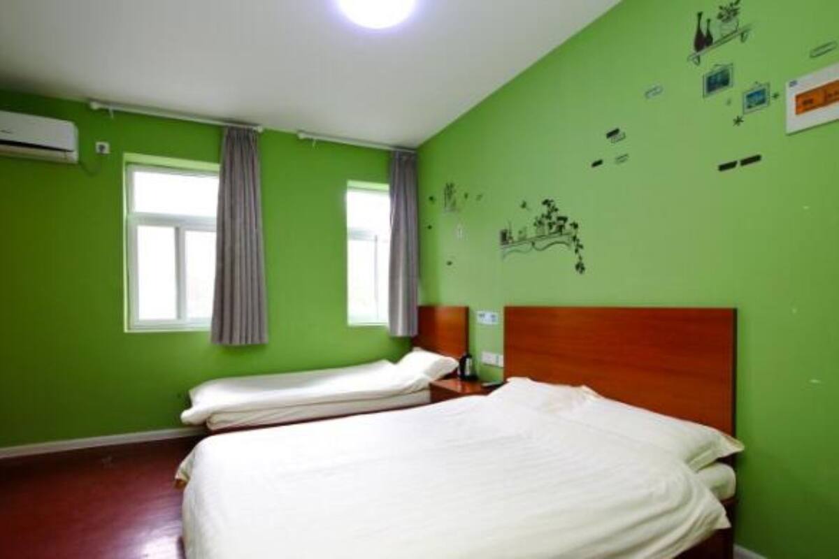 Ein Zimmer mit grünen Wänden, einem Holzkopfteil, einem Bett, einem Fenster mit Vorhängen und einer Klimaanlage.