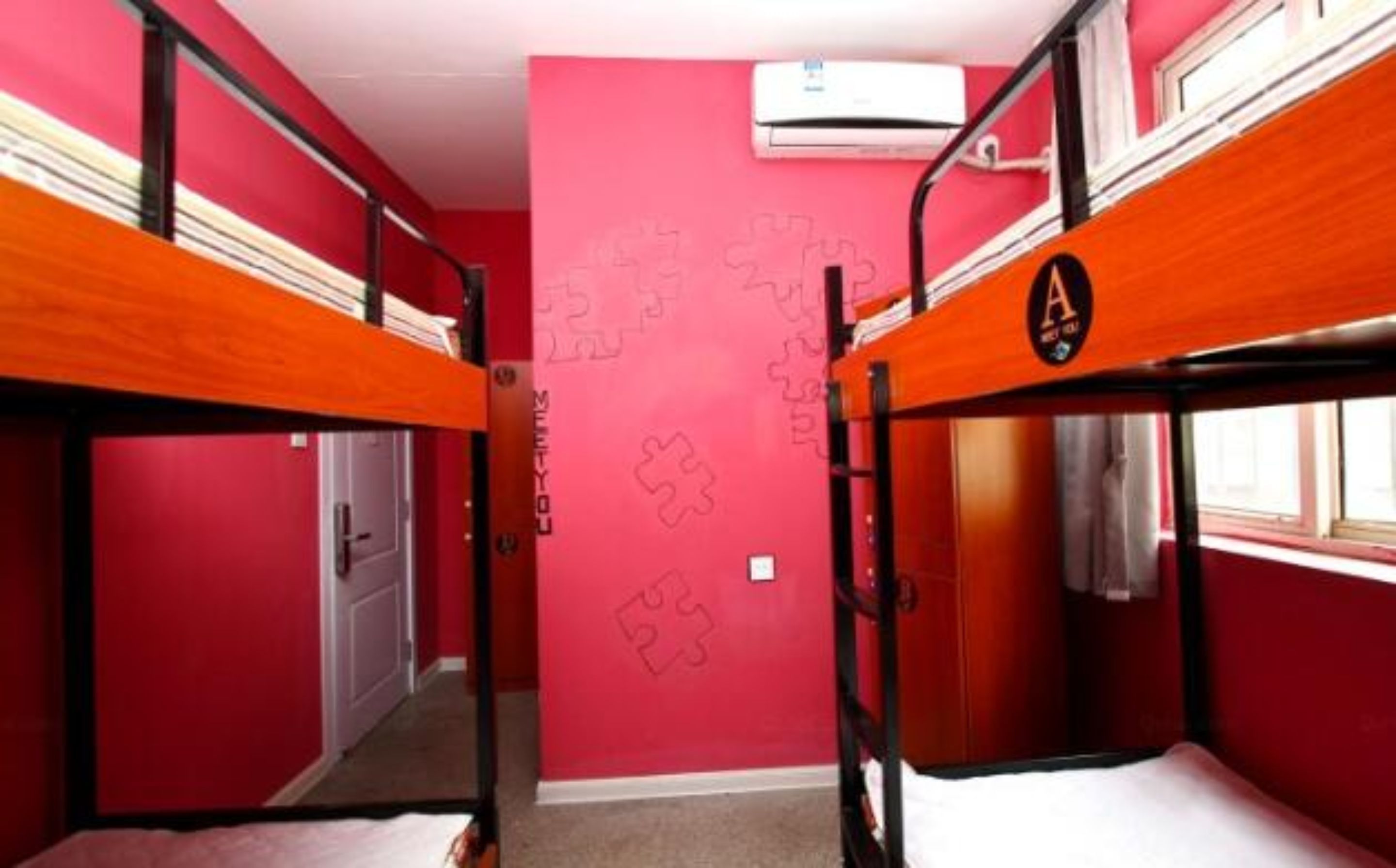 A room with bunk beds, a door, and a wall with puzzle pieces.