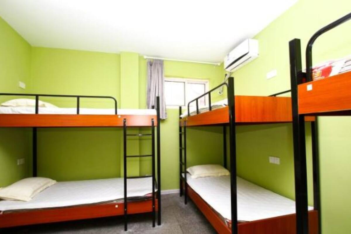 Ein Schlafsaalzimmer mit Etagenbetten, grünen Wänden und einer Klimaanlage.