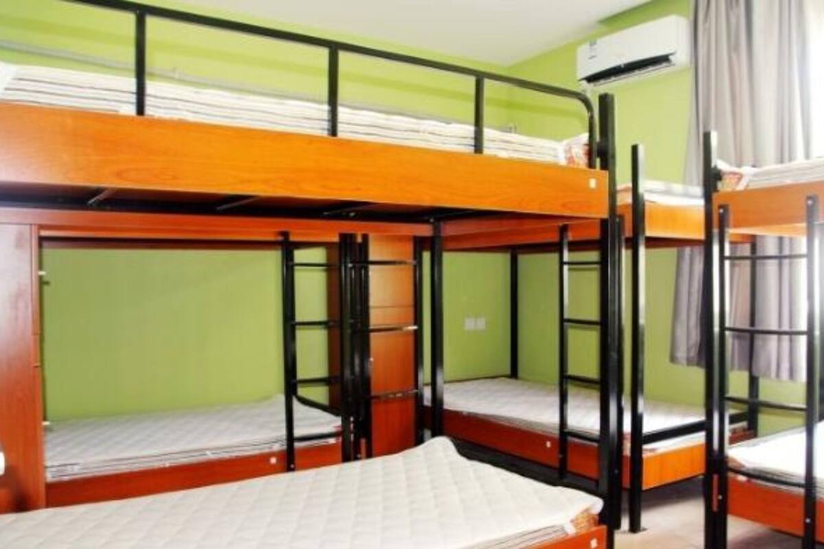 Ein Schlafsaalzimmer mit Etagenbetten, grünen Wänden und einer Klimaanlage.