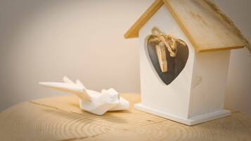 A small white birdhouse with a heart-shaped window and a rope tied around the roof.