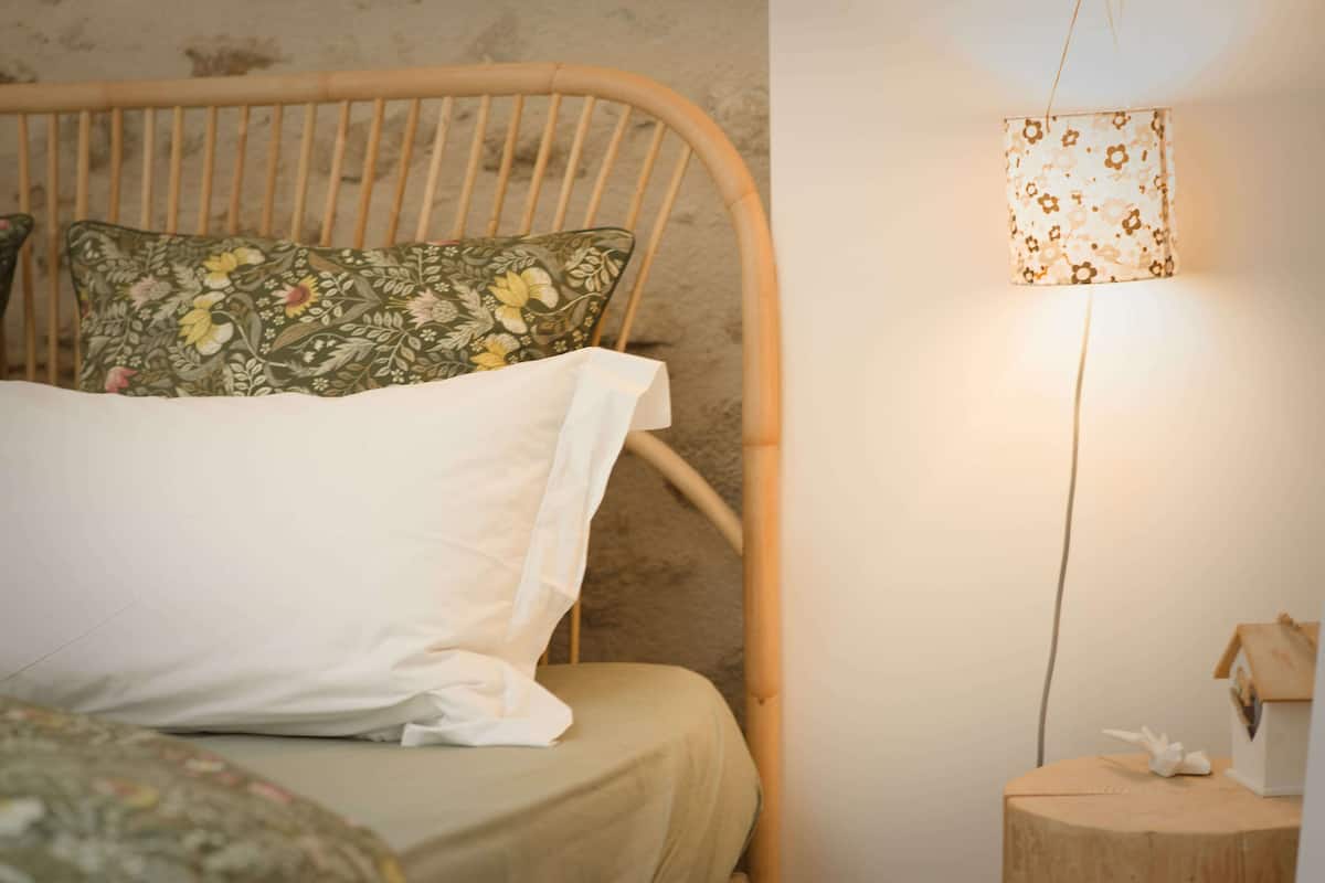 Una cama con un cojín floral y una mesita de noche con una lámpara.