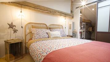 Un dormitorio con techo de madera, una cama con ropa de cama floral y una manta roja.