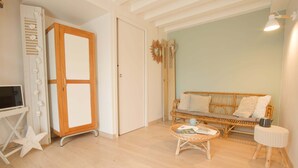 Una habitación con un armario de madera, un sofá de mimbre, una pequeña mesa redonda y un adorno con forma de estrella.