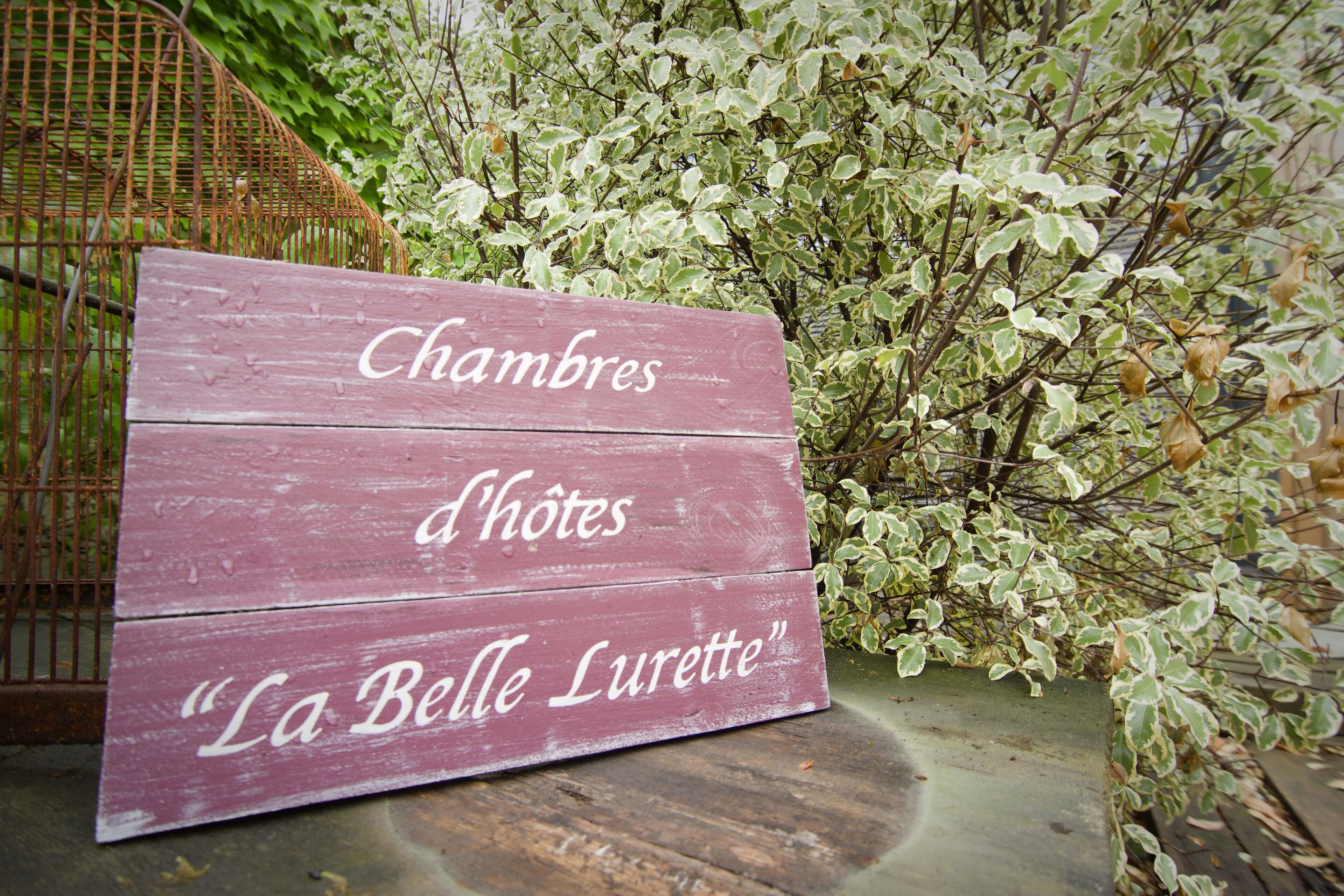 Un letrero de madera con el texto 'Chambres d'hôtes 'La Belle Lurette'.