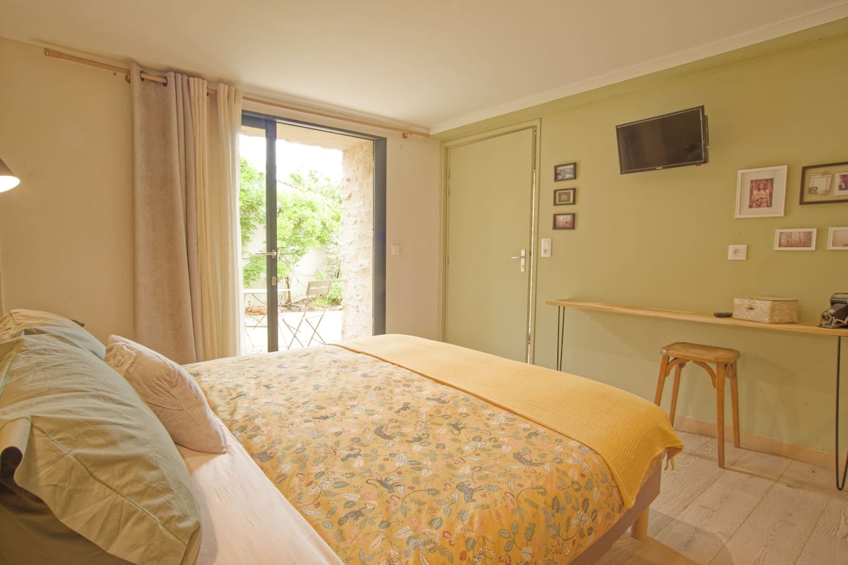 Un dormitorio con cama, escritorio y televisor en la pared.