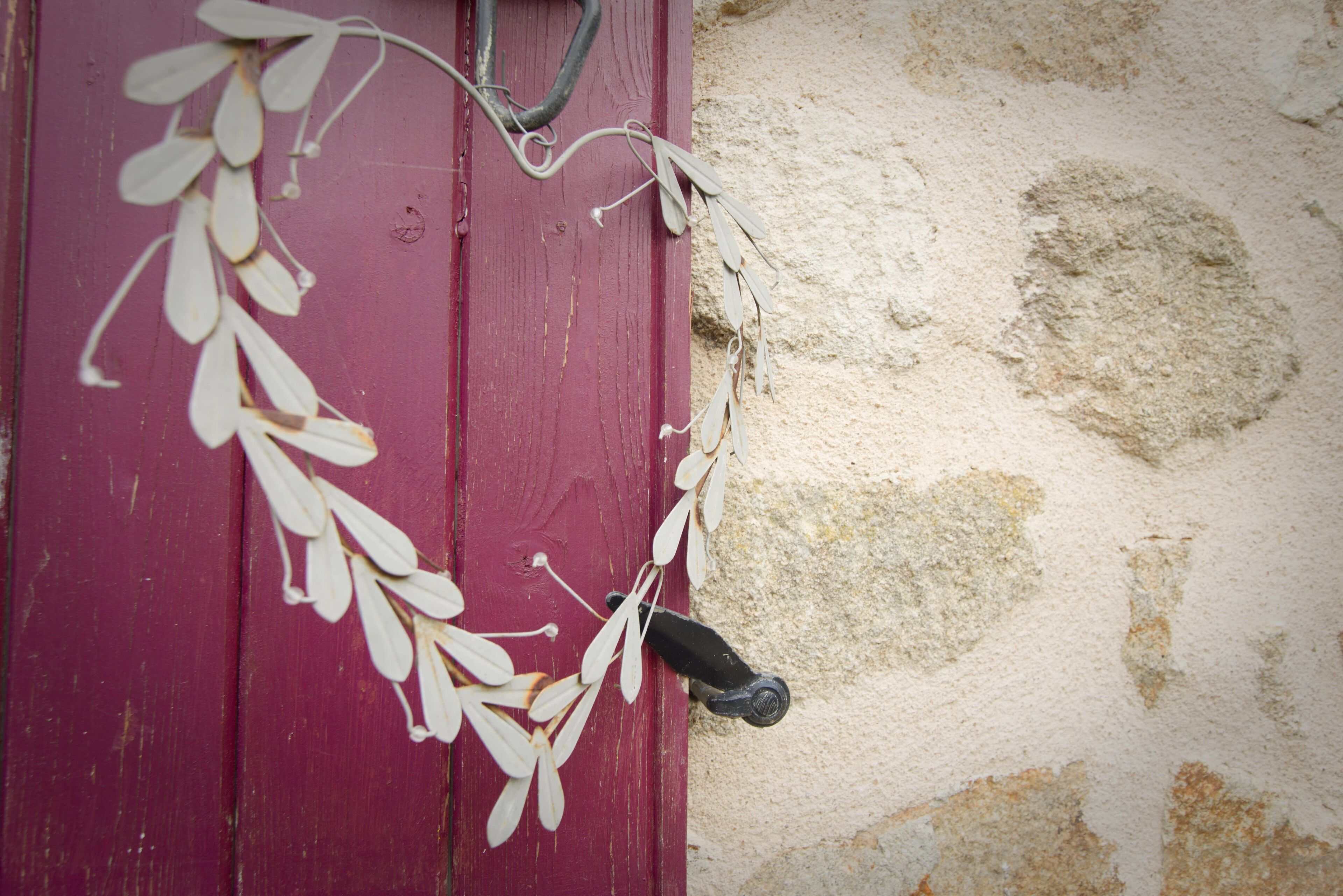 A red door with a decorative vine and a black handle.