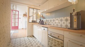 Una cocina con armarios blancos, una cafetera y un salpicadero de azulejos.