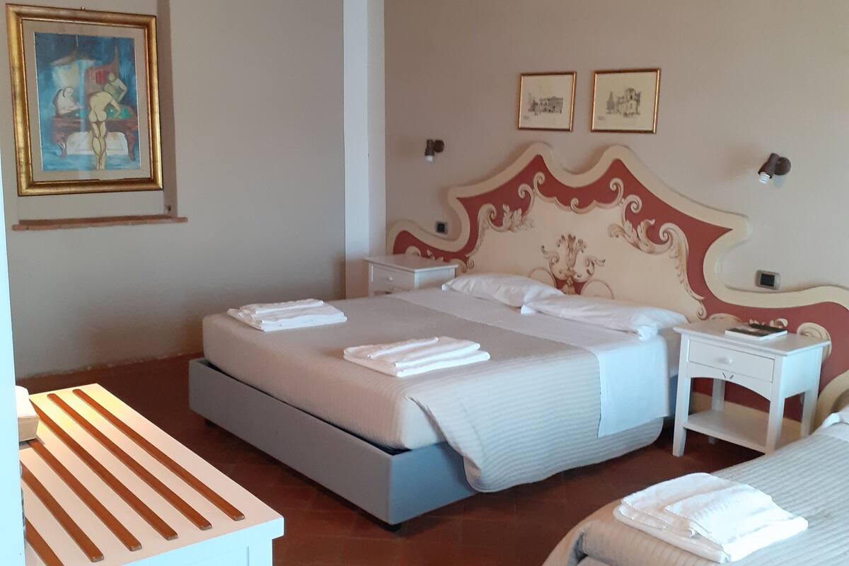 Un dormitorio con dos camas, una mesita de noche, un cuadro y suelo de baldosas.