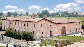 A large, historic building with multiple arched windows and a central door, surrounded by a well-maintained lawn and a clear sky. - Corte Breda Agriturismo Bed & Breakfast (Chiari)