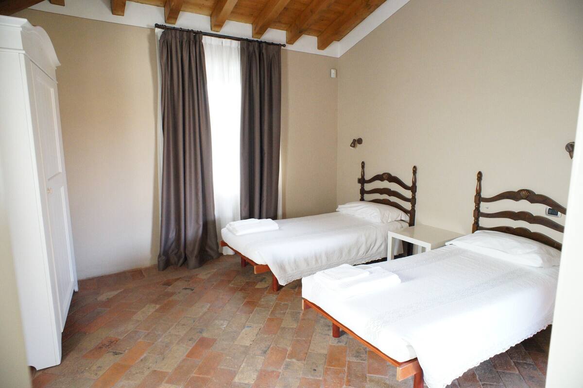 Un dormitorio con dos camas individuales, una mesita pequeña y un armario.